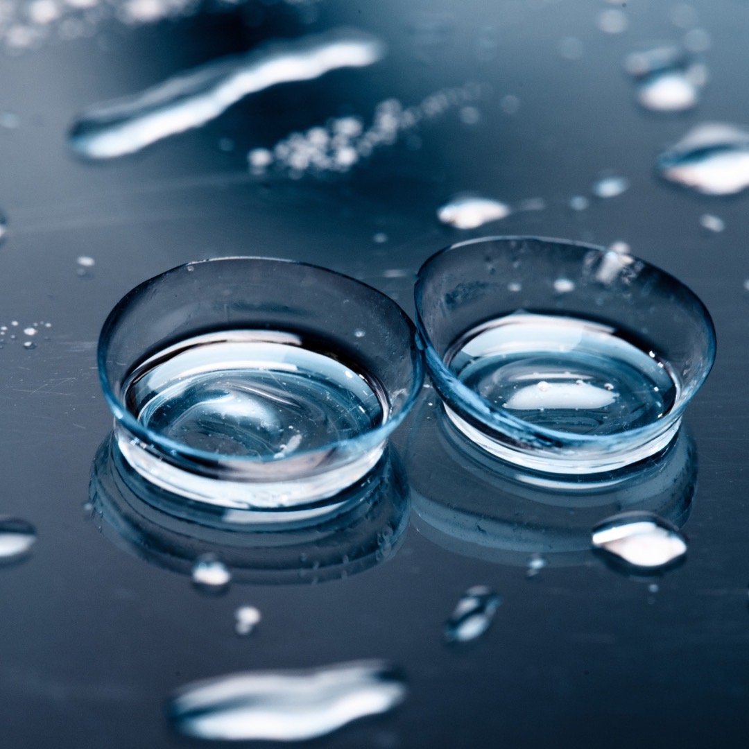 Lentes de contacto sobre una superficie metálica con gotas de agua